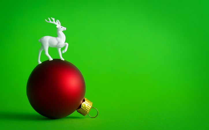 Red bauble decoration on green background with reindeer