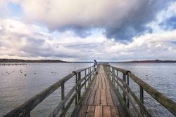 Woman standing on a bridge over Alpine lake