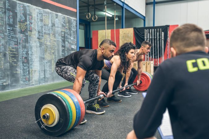 Fit team lifting weights in the gym with their coach