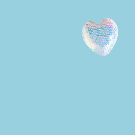 Iridescent sequins heart on blue background