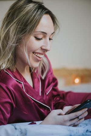 Woman lying down on bed with smartphone