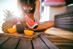A platter of sliced watermelon, pineapple and oranges with a woman in a bikini