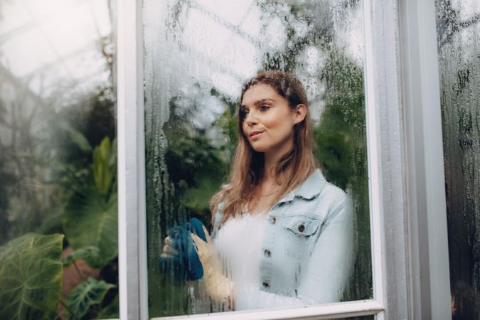 Portrait of woman standing inside greenhouse with condensation on the glass