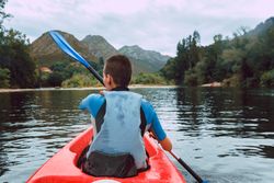 Female kayaking with paddle in raised hands
