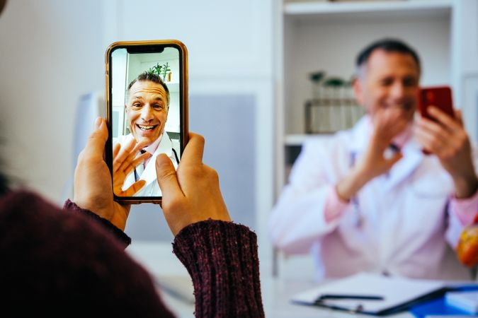 Smiling physician taking video call with patient from his office