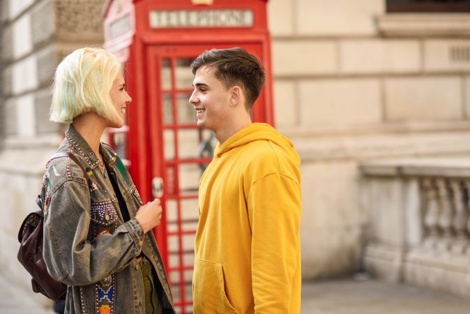 Cute couple looking at each other in front of a phone booth