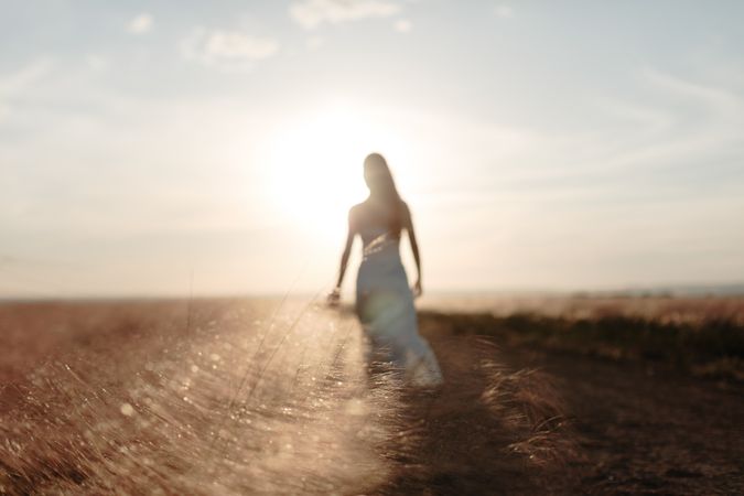 Blurred view of young woman in a dress standing in an open field