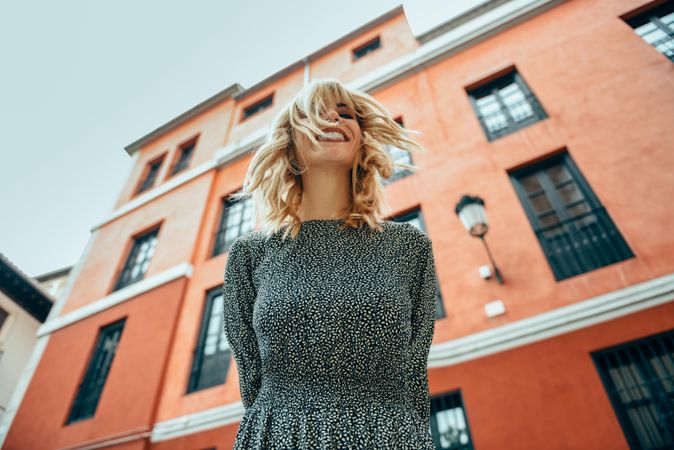 Looking up at blonde woman standing by red building