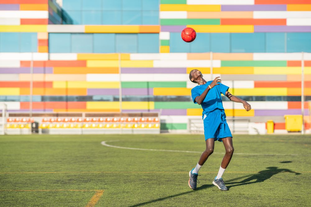 Black teenager jugging football ball on head