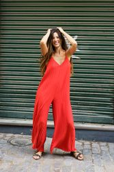 A Stylish and Trendy Young Woman in a Bright Red Jumpsuit Posing Happily Outdoors