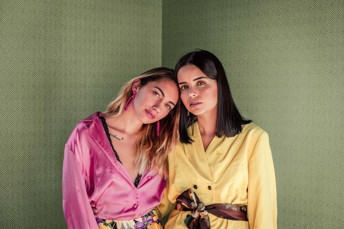 Young trendy women in bright clothes looking at camera