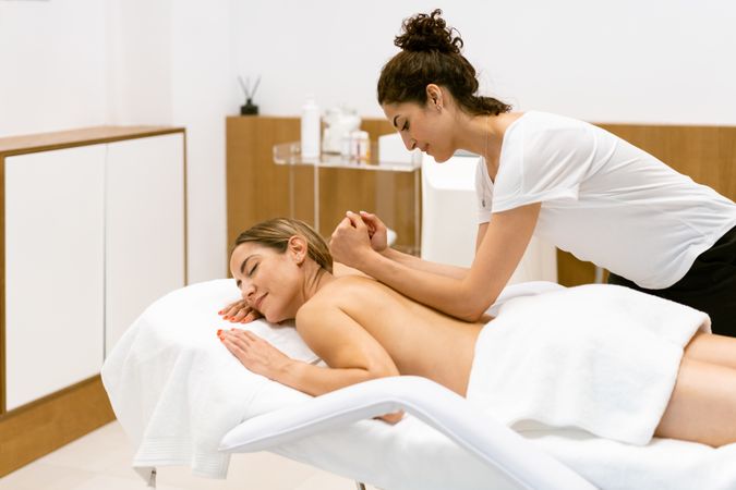 Masseuse putting elbow on female clients back during a relaxing massage