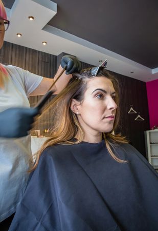 Hairdresser taking strands of client's hair to dye
