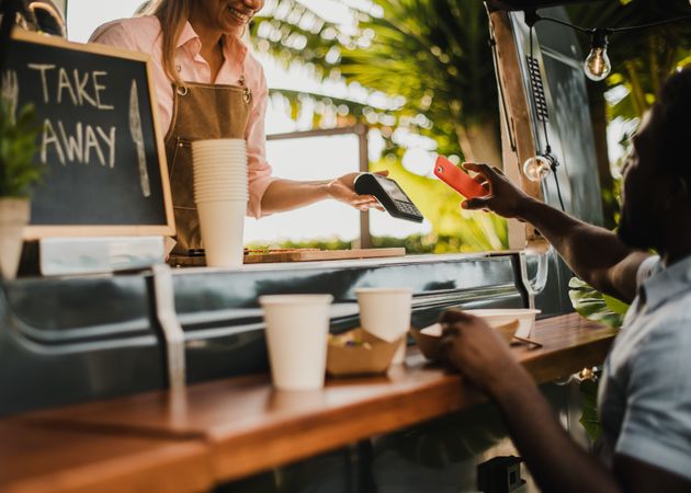 Black man making contactless payment at food truck restaurant - Focus on hand holding smartphone