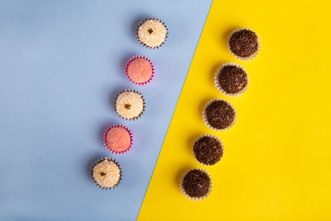 Top view of two rows of different flavored truffles on blue yellow duo tone background