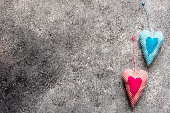 Two blue and pink felt heart ornaments on grey counter