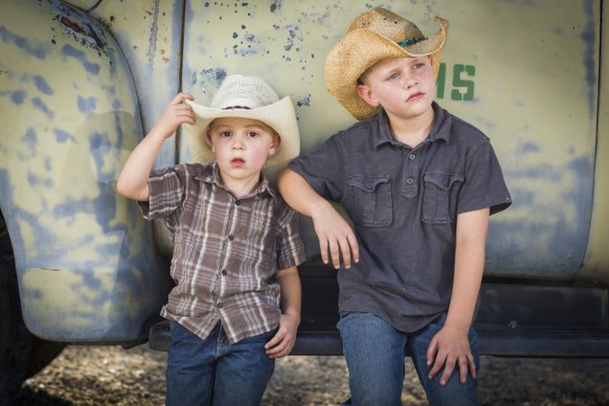 Two Young Boys Wearing Cowboy Hats Leaning Against Antique Truck.