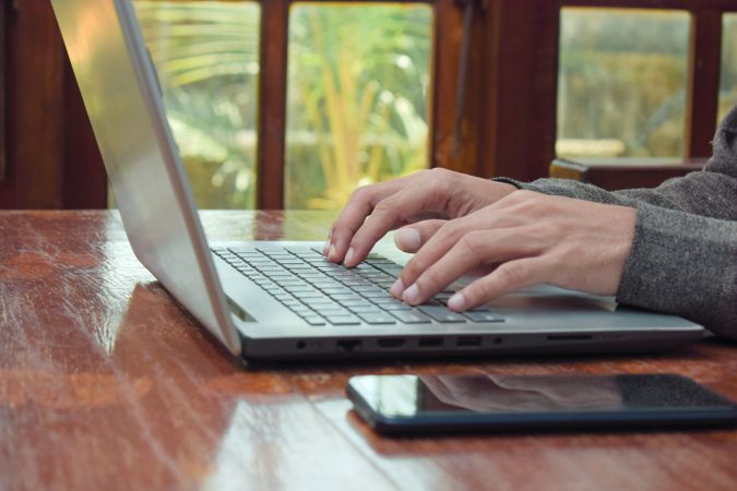 Side view of man typing on laptop on table in livingroom
