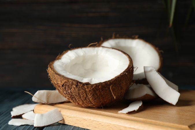 Board with coconut on wooden background, close up
