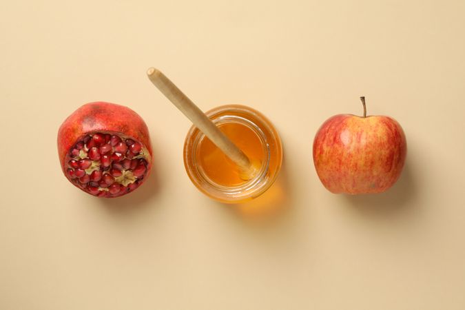 Looking down at row on pomegranate, honey pot and apple