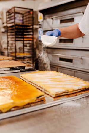 Crop confectioner spilling sugar on cake