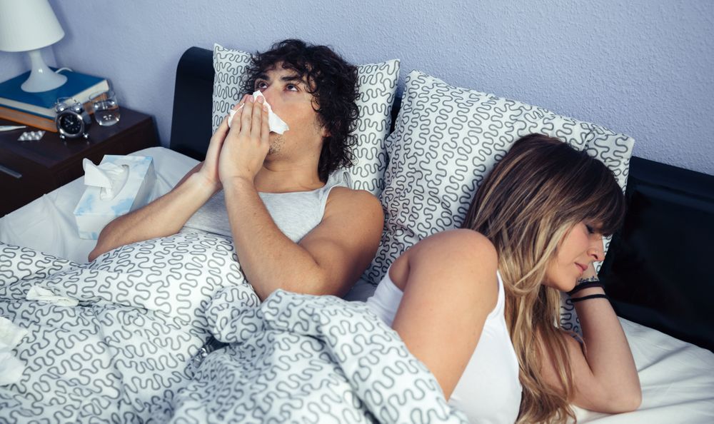 Sick man sneezing and blowing nose with tissue