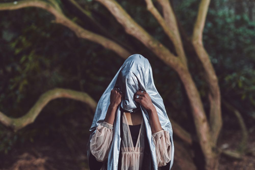 Woman holding blue metallic sheet over her head