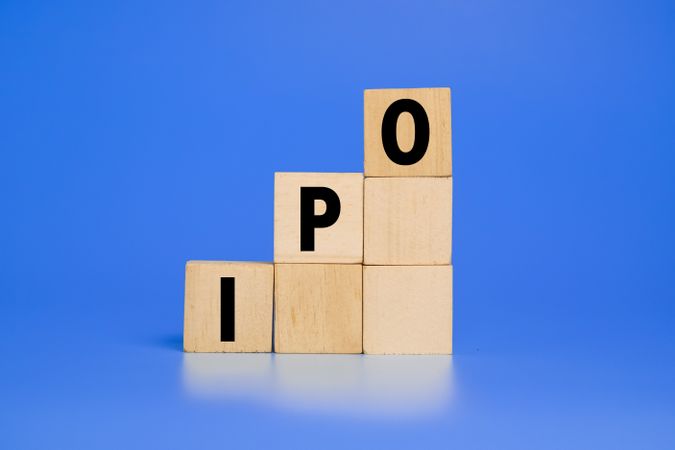 IPO letter text or initial public offering words on wooden blocks isolated on blue background copy space