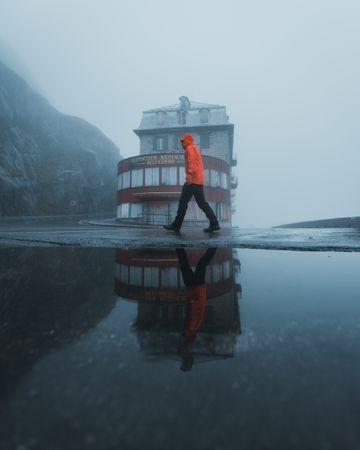 Man in orange jacket walking in the rain