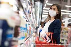 Woman placing items in basket at grocery shopping in surgical mask 4Oona4
