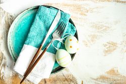 Top view of Easter table setting with ceramic teal plates and spotted Easter eggs