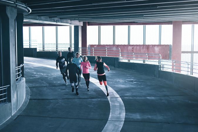 Multi-ethnic group of people working out by running in concrete track