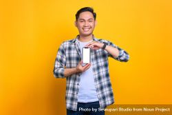 Happy Asian male showing blank screen of smart phone with both hands in studio shoot 5k79D5