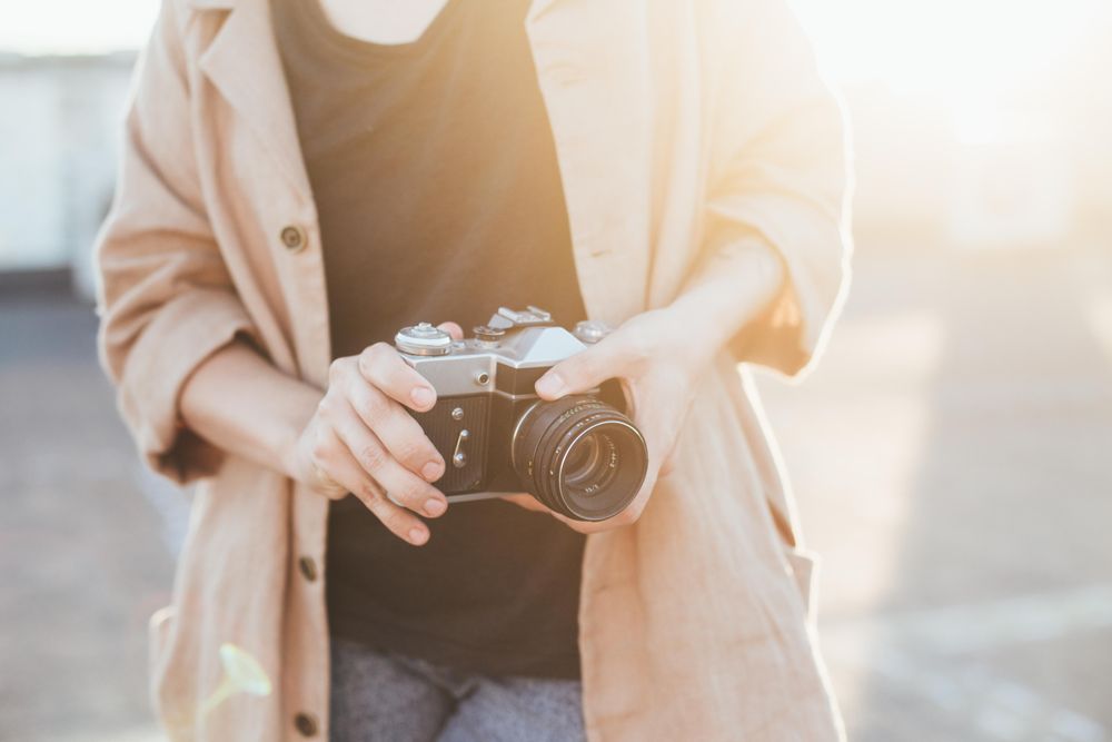 Woman holding vintage camera outside