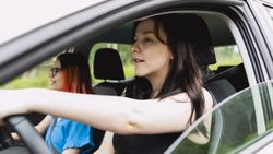 Two people happily travel by car, one of them driving, during a weekend getaway