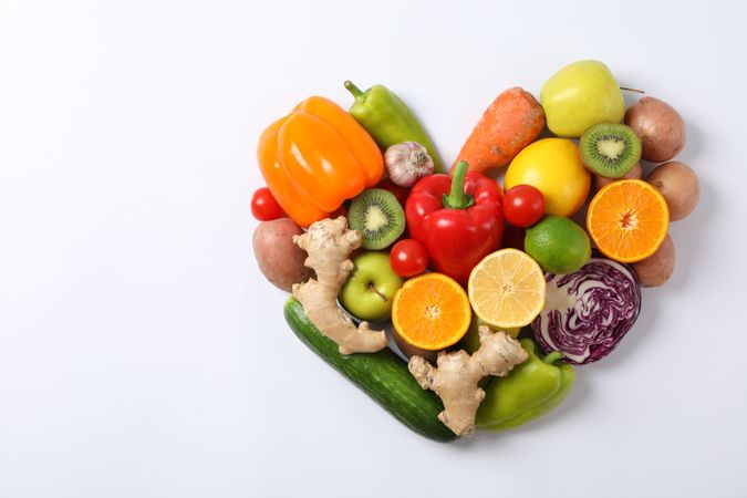 Heart laid out of vegetables and fruits on plain background, copy space