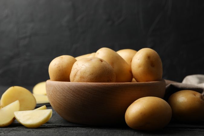 Bowl of potatoes in dark kitchen, copy space