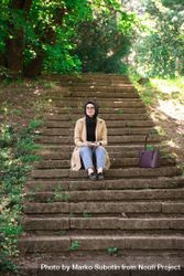Woman sitting on outdoor stairs looking up from book be6Mq0