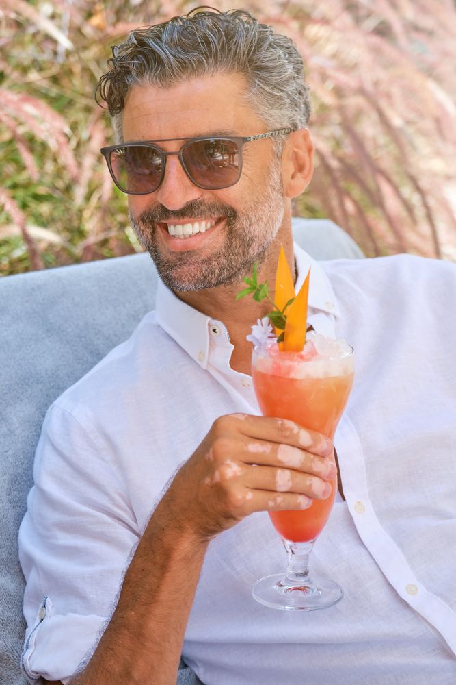 Cheerful man with cocktail sitting on bench