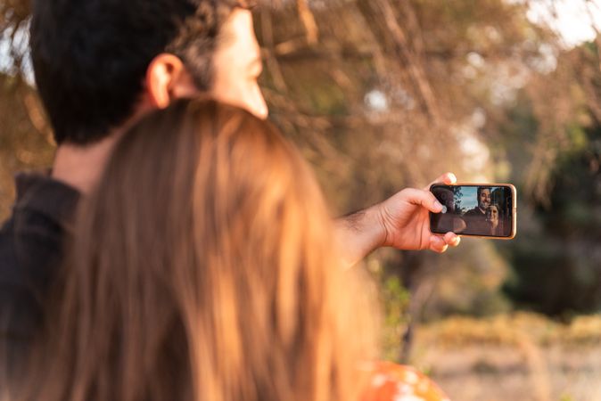 Couple kissing and taking photo outdoors