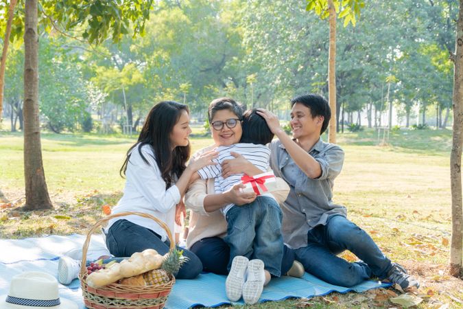 Family celebrating grandmother’s birthday with a picnic in the park
