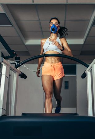 Fit young woman running on treadmill with a mask at a sports science lab