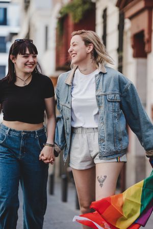 Lesbian couple with LGBT flag walking on street