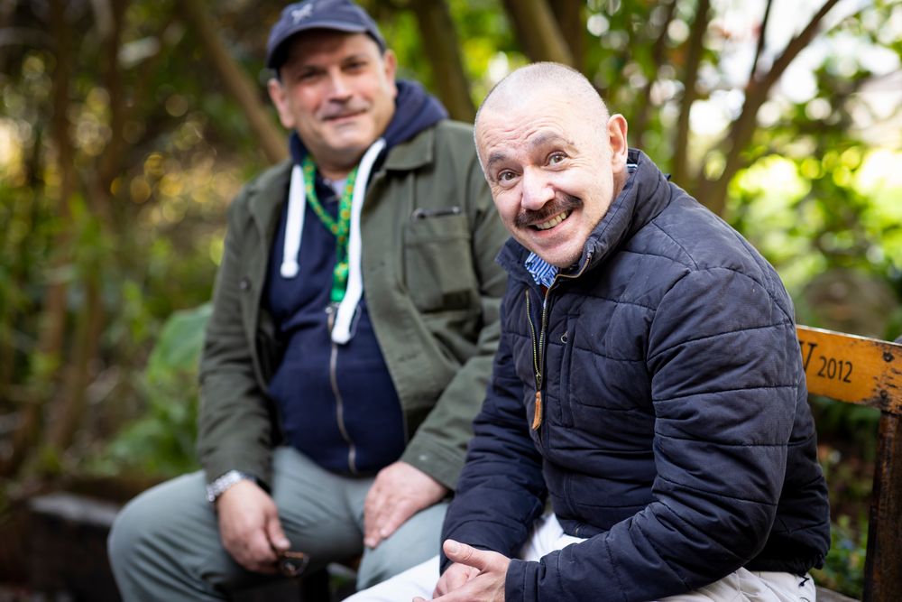Two male friends sitting outside on a park bench