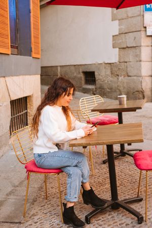 Young woman using smartphone in outdoors cafe