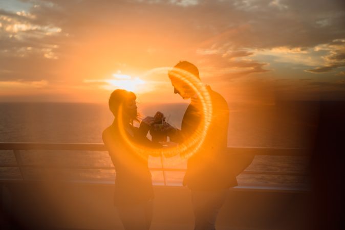 Young people kissing in sunset light on ship