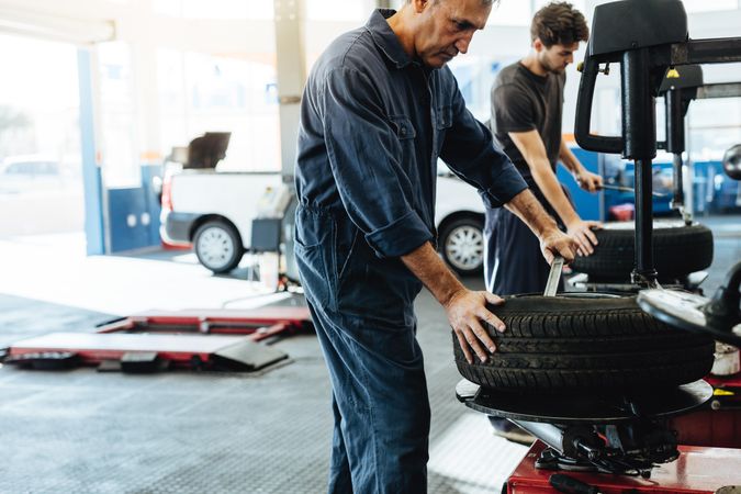 Two skilled automobile technicians working on tire machine