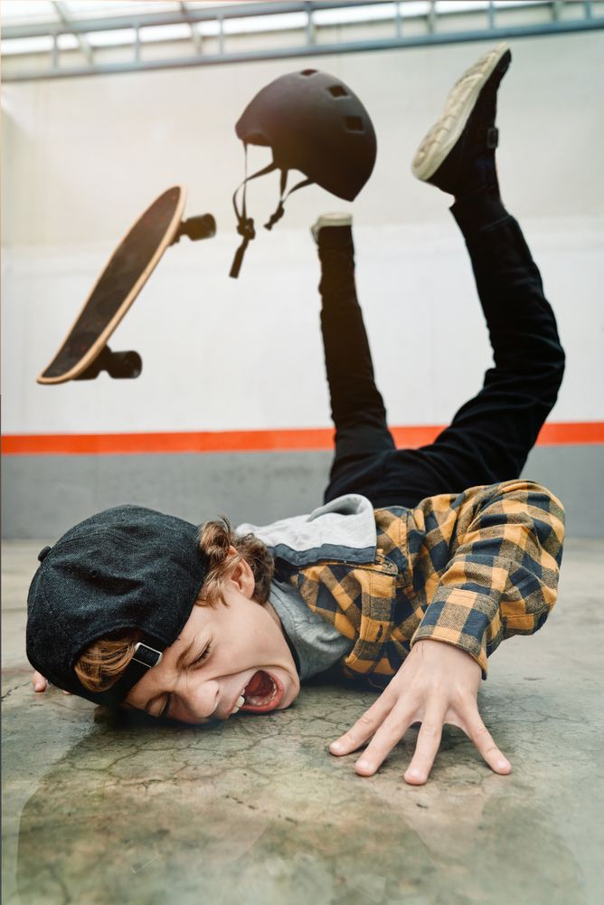 Boy falling from skateboard on concrete ground