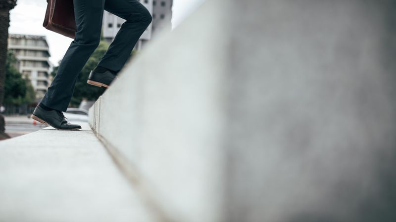 Low angle view of legs of man climbing up the steps outdoors
