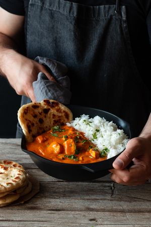 Faceless cook holding frying pan with hot butter chicken